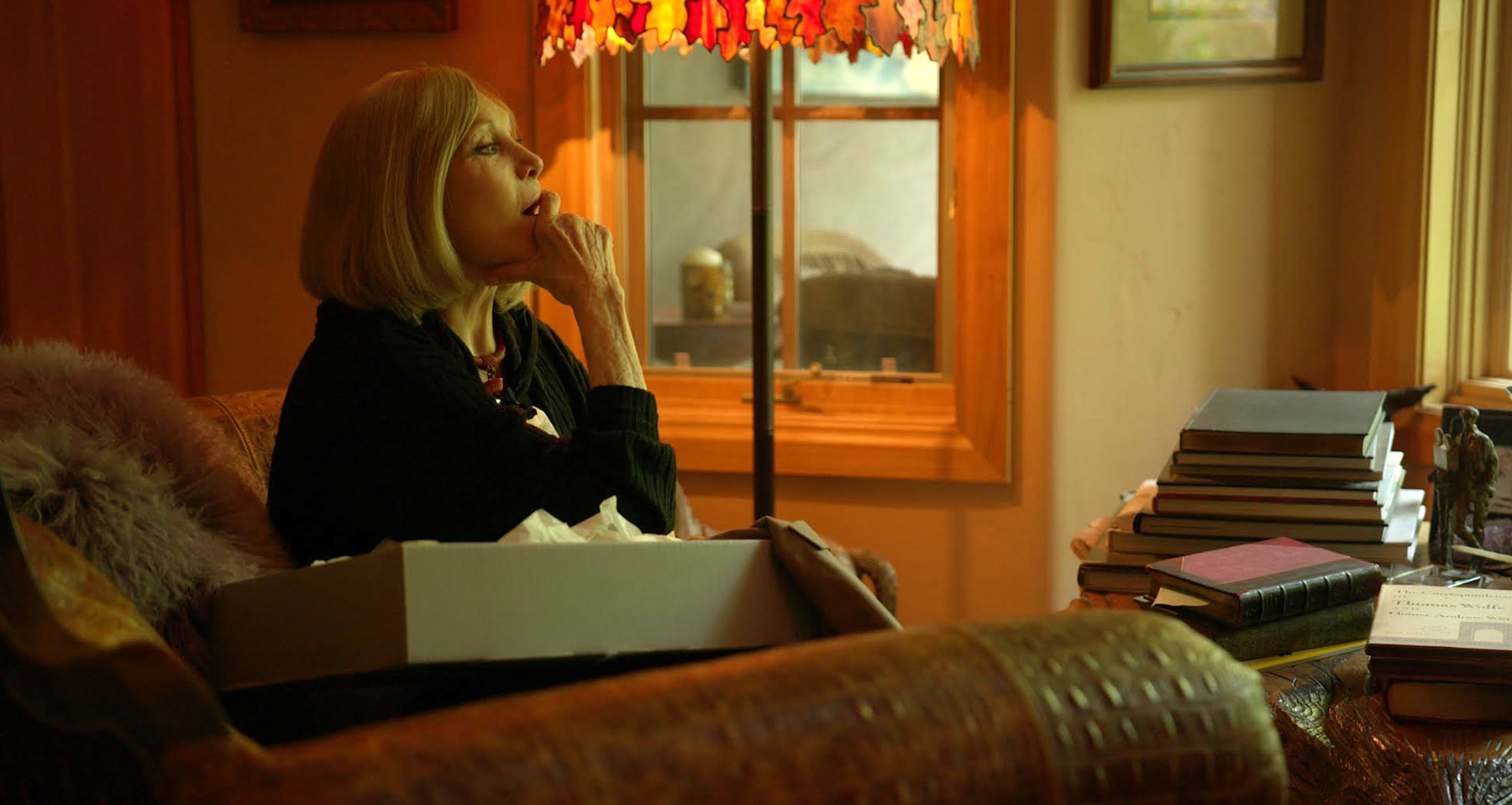 Movie still of Kim sitting by the fireplace